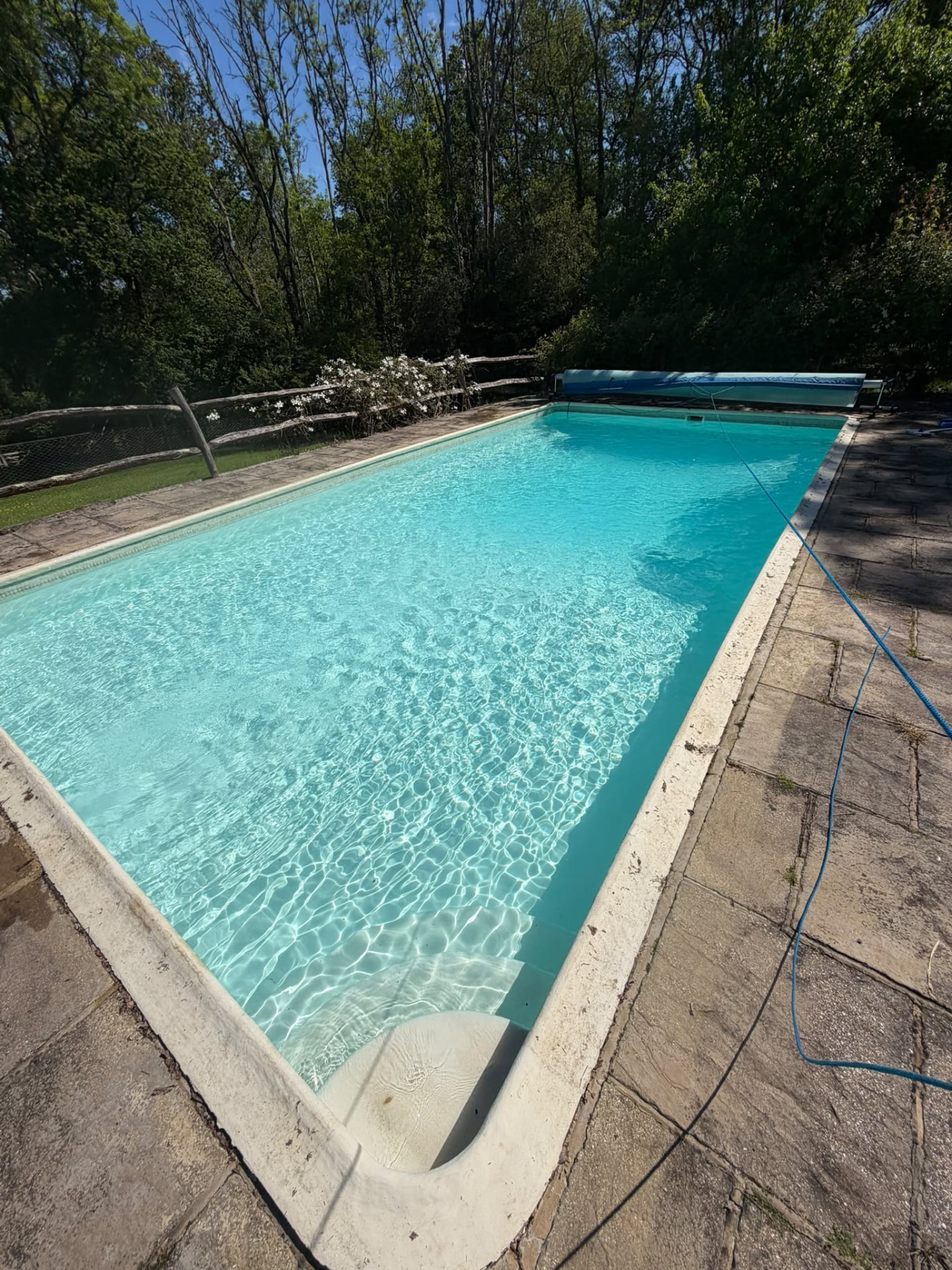 Long outdoor swimming pool with cover roller at the far end