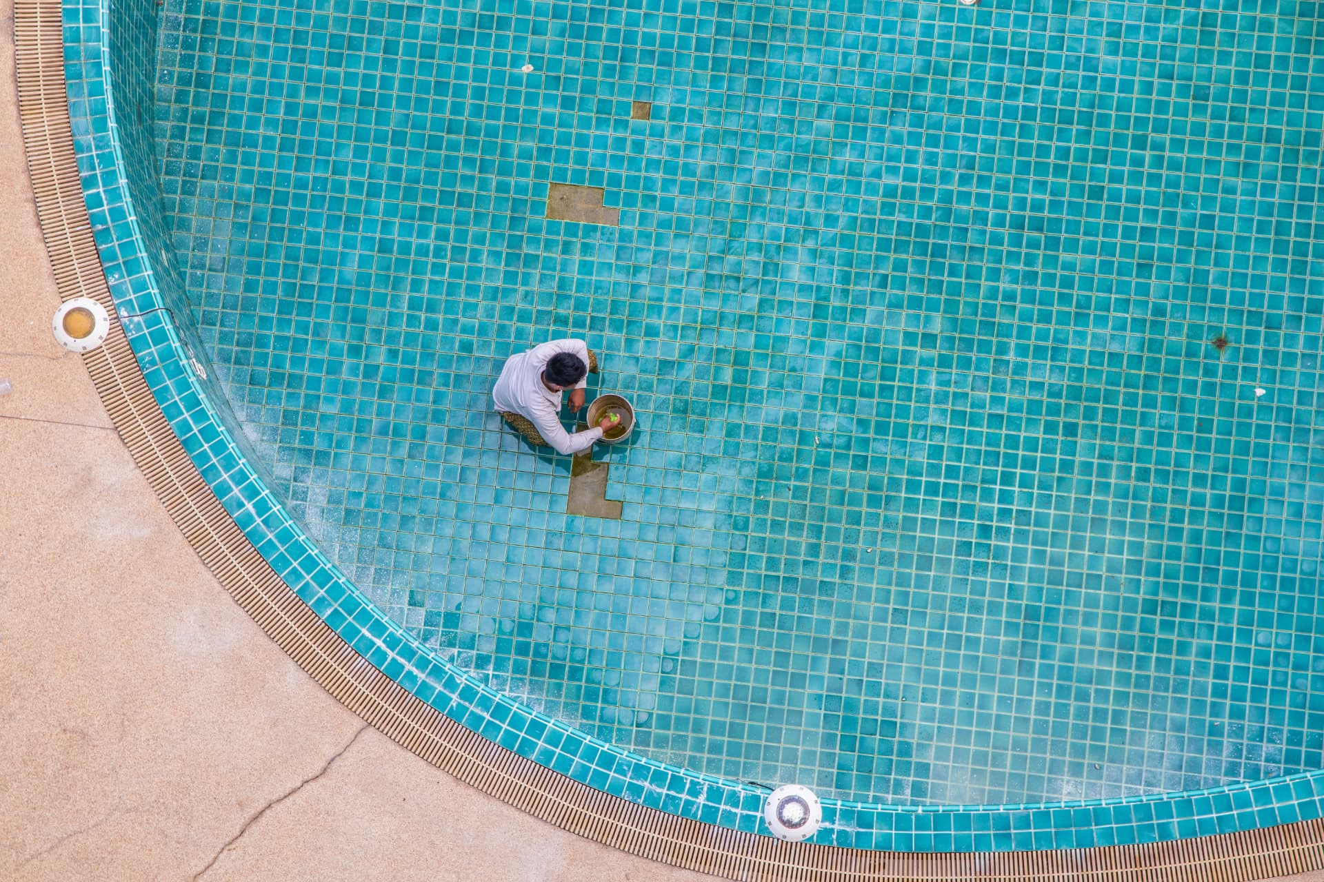 Large drained commercial pool being cleaned and tile-repaired