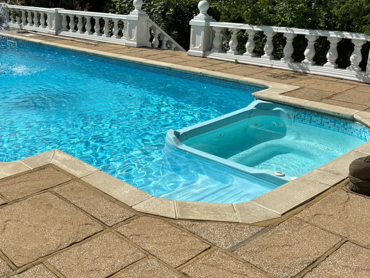 Built-in spa hot tub with jets beside a garden swimming pool