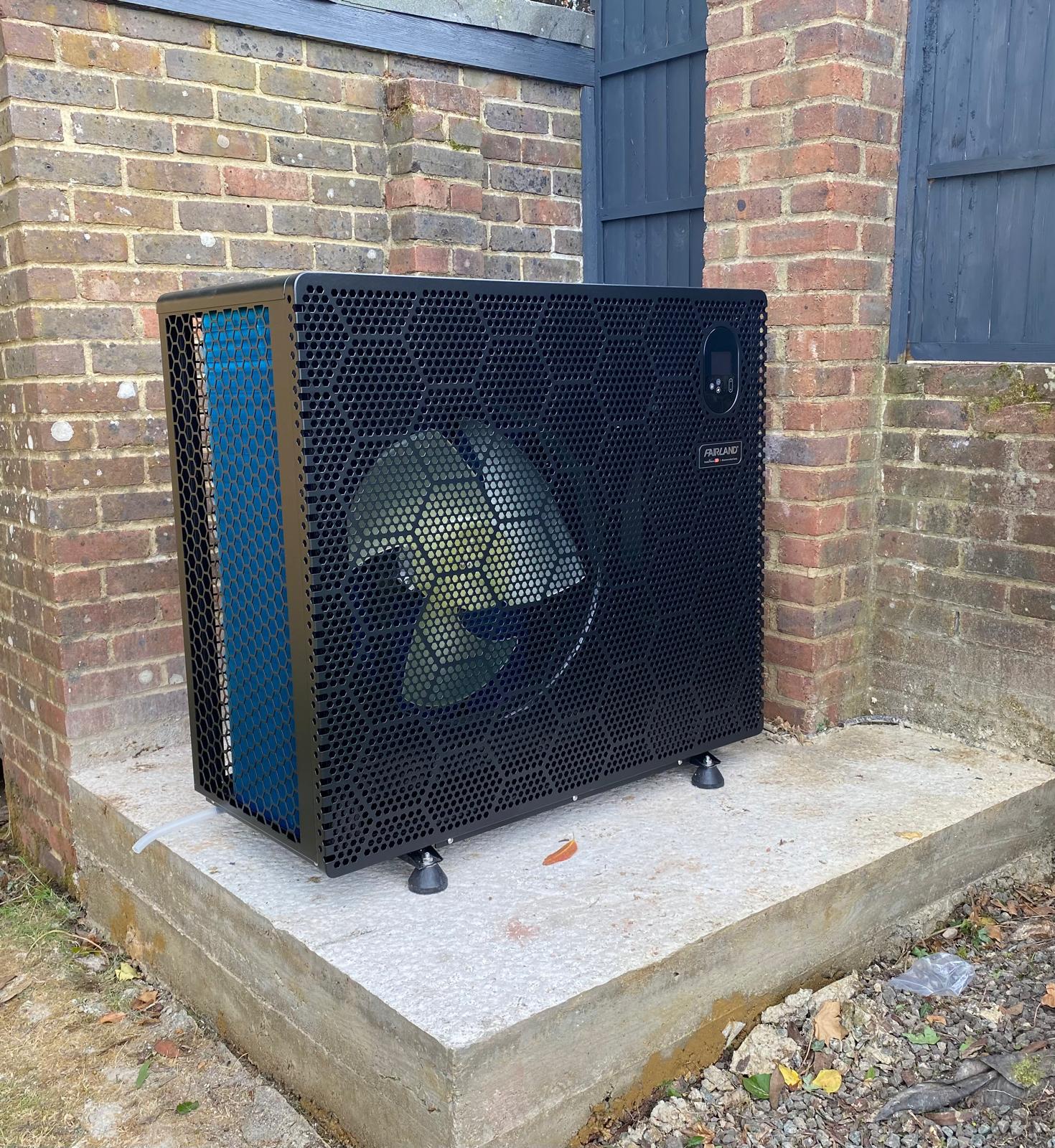 Pool heat pump installed against a garden wall for swimming pool heating