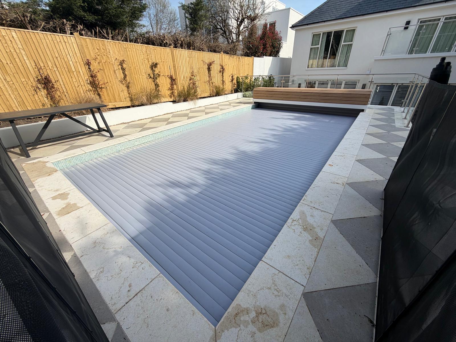 Garden swimming pool with grey slatted automatic cover