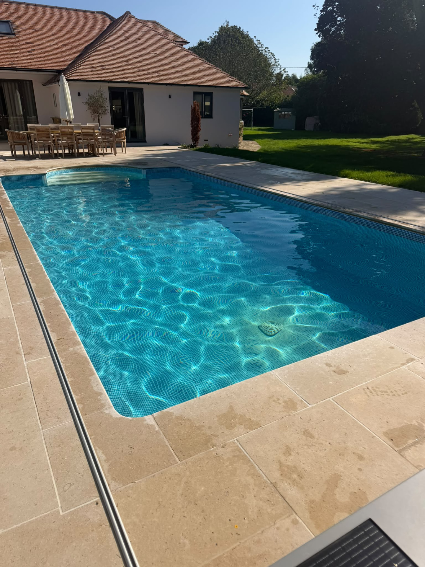 Outdoor swimming pool beside a modern house and garden