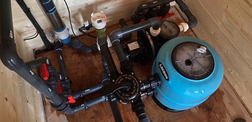 Newly re-piped pool plant room with blue sand filter, pump and grey pipework