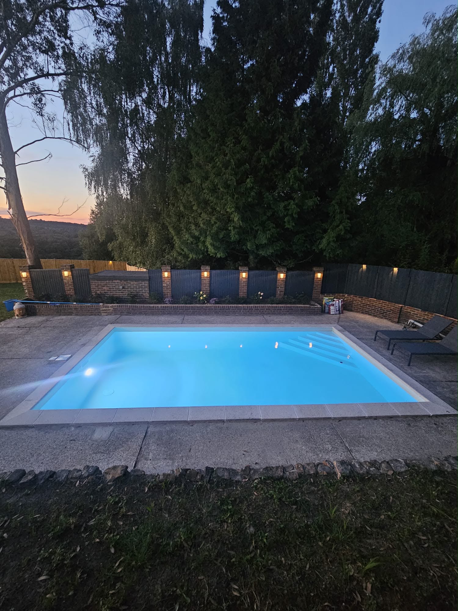 Newly built garden swimming pool lit up at dusk