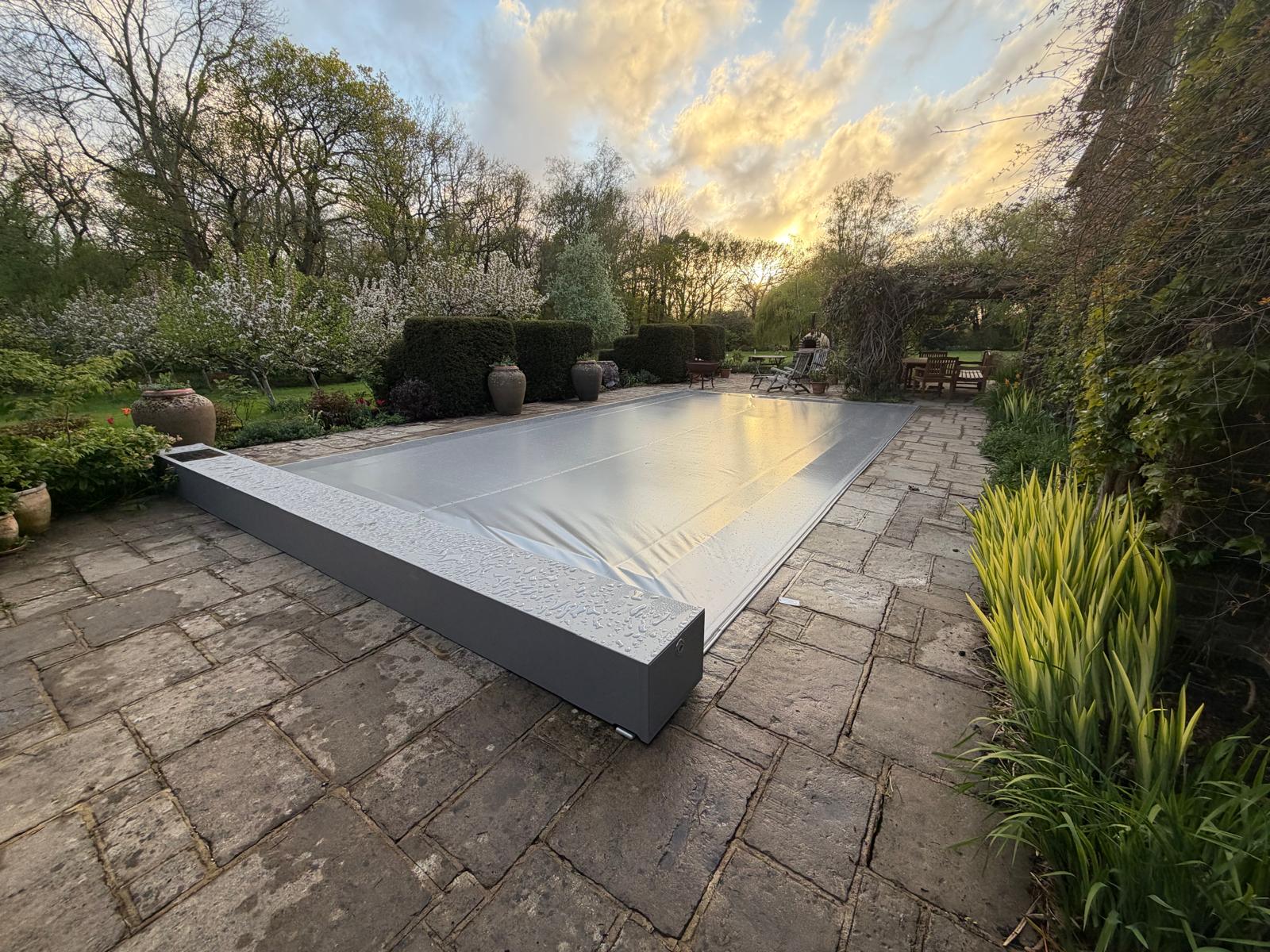 Garden swimming pool with a grey automatic pool cover closed