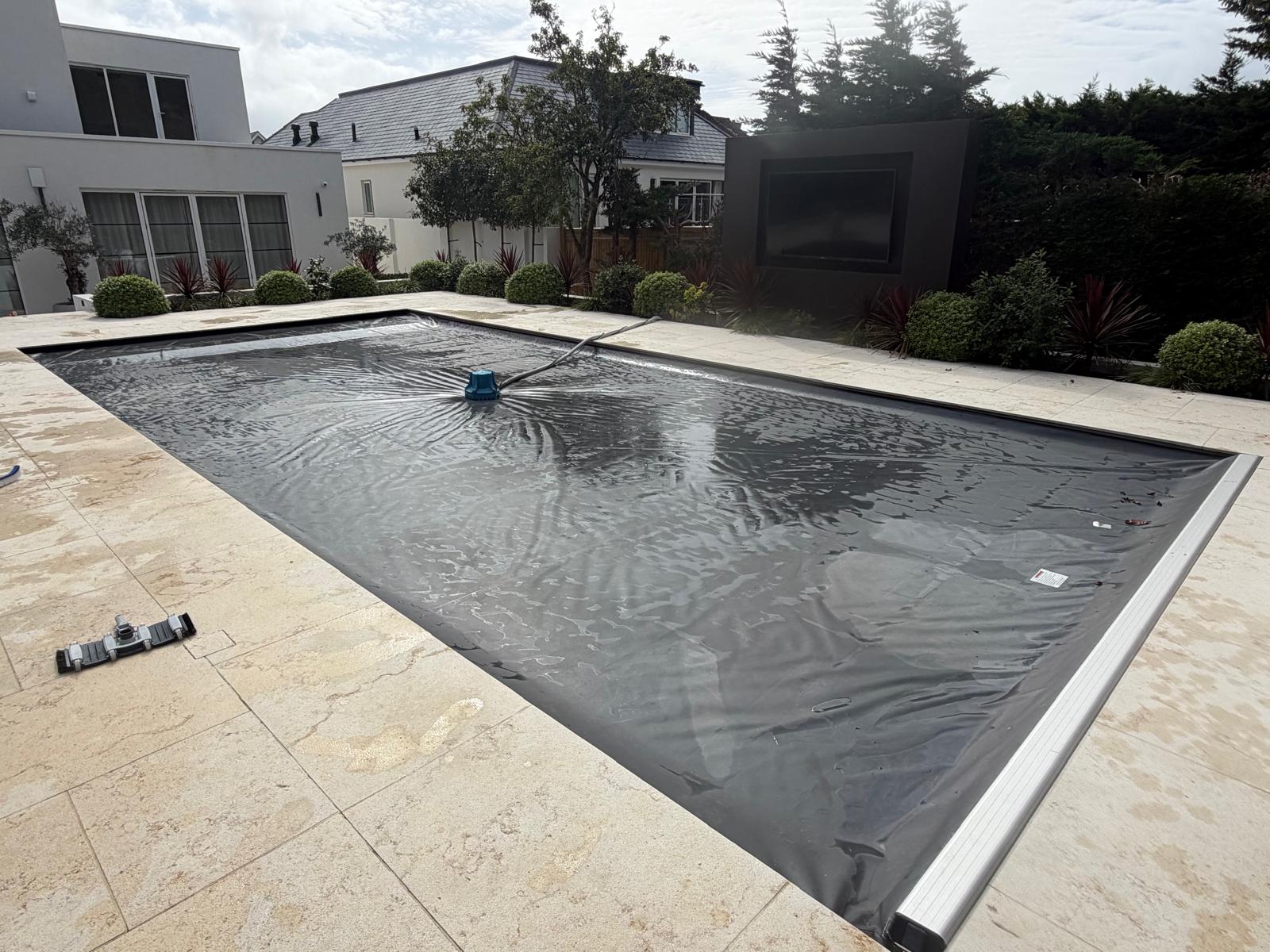Outdoor swimming pool closed for winter under a dark safety cover