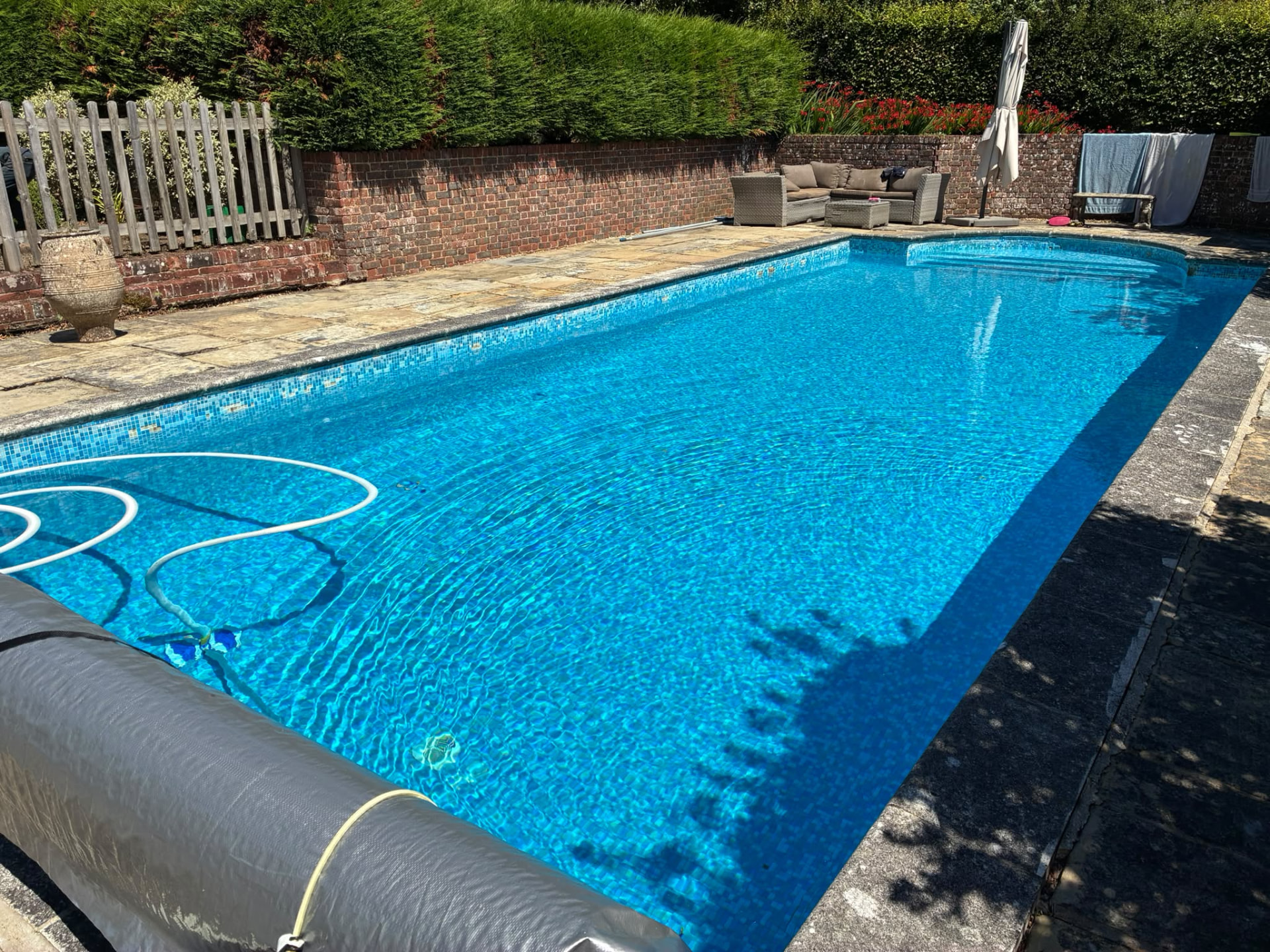 Bright blue swimming pool cleaned with a vacuum hose during servicing