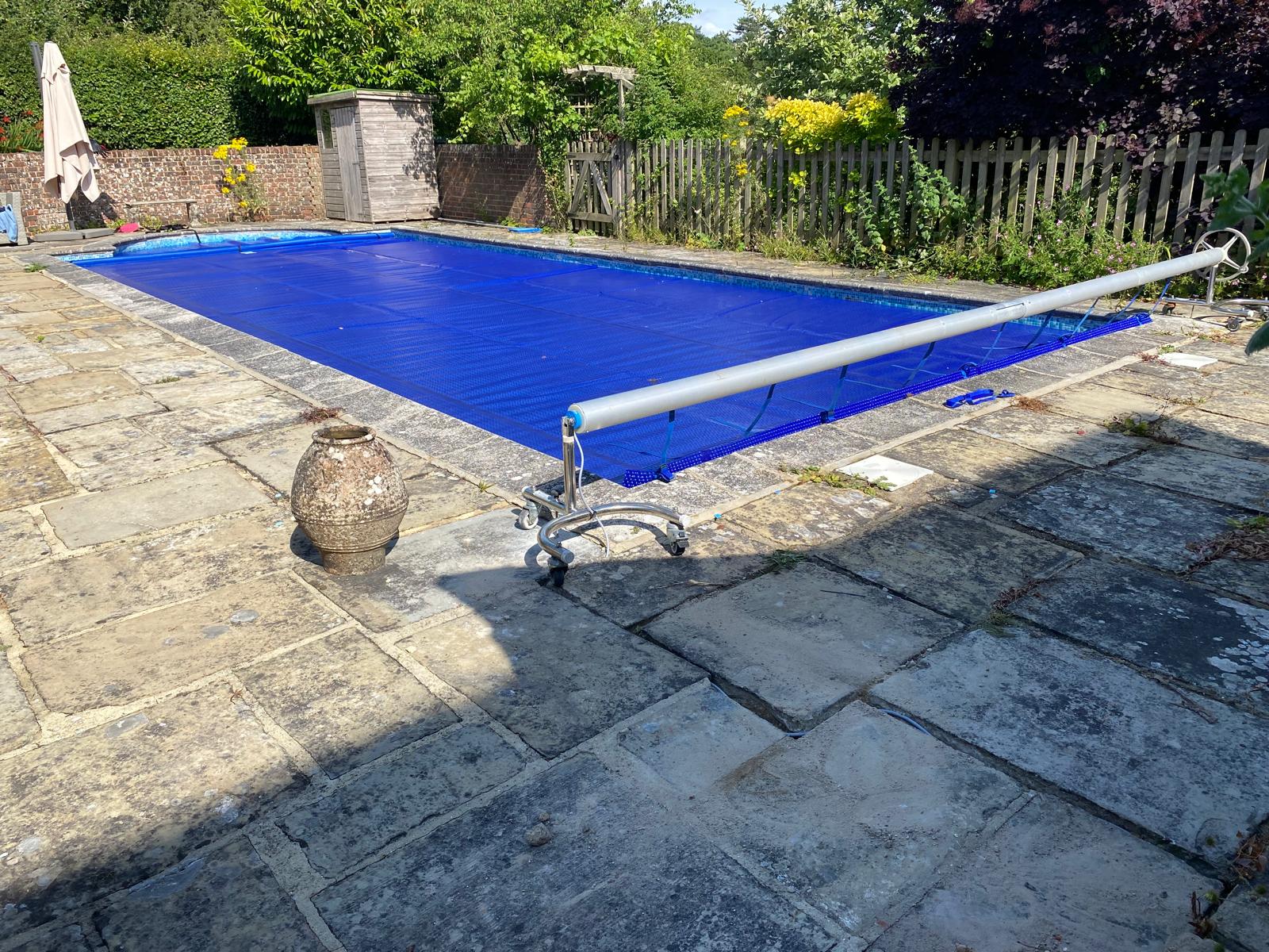 Outdoor pool with blue solar cover on a roller