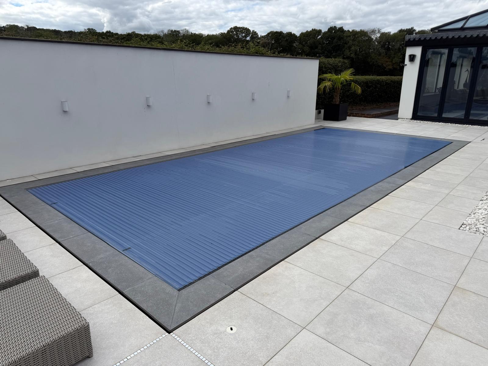 Rectangular swimming pool with a blue slatted automatic cover